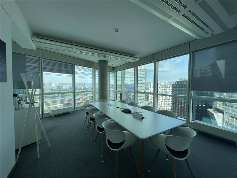 Geräumiger Konferenzraum mit modernem Mobiliar und Panoramablick auf die Stadt und den Fluss.