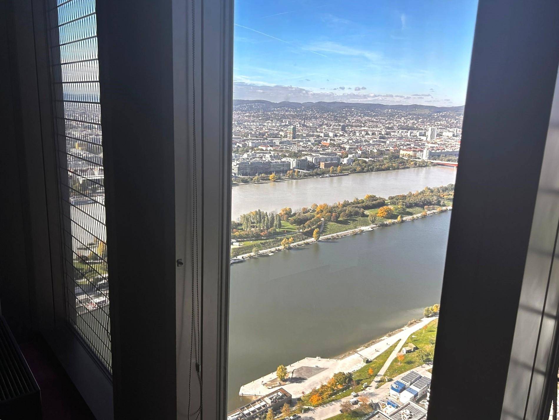 Panoramablick auf die Stadt und den Fluss von einem hohen Fenster aus, mit viel Tageslicht.