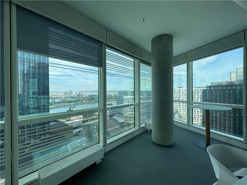 Heller Bürobereich mit Säule, kleinem Tisch und weitem Blick auf die Stadt und den Fluss.