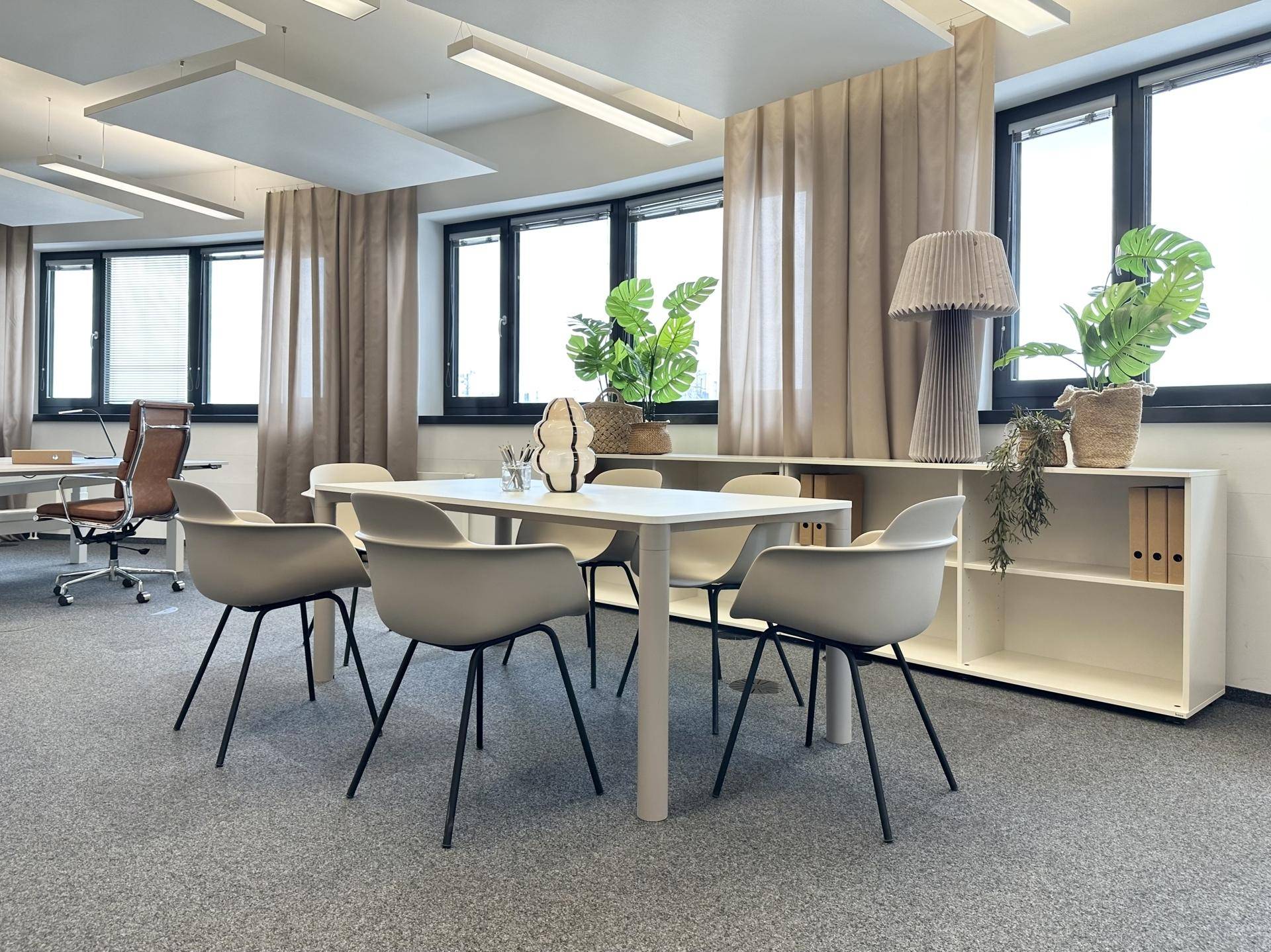 Besprechungsbereich in einem modernen Büro mit runden Stühlen, einem Tisch und Pflanzen als Dekoration.