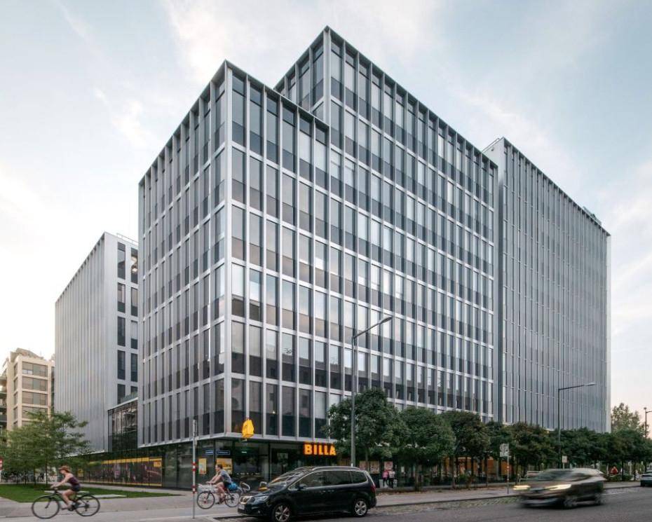 Großes Bürogebäude mit moderner Architektur und reflektierenden Fensterfronten bei Tageslicht.