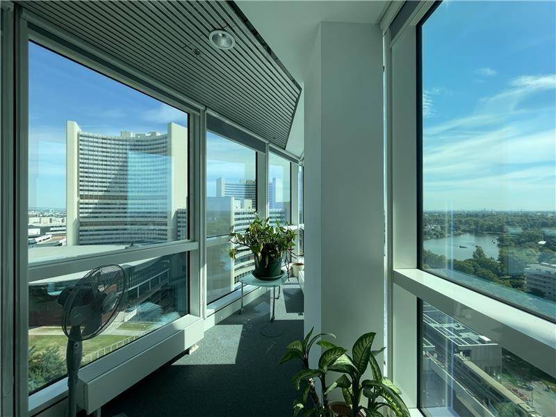 Helle Loggia mit Pflanzen, Ventilator und weitem Blick auf die Stadt und den Fluss.