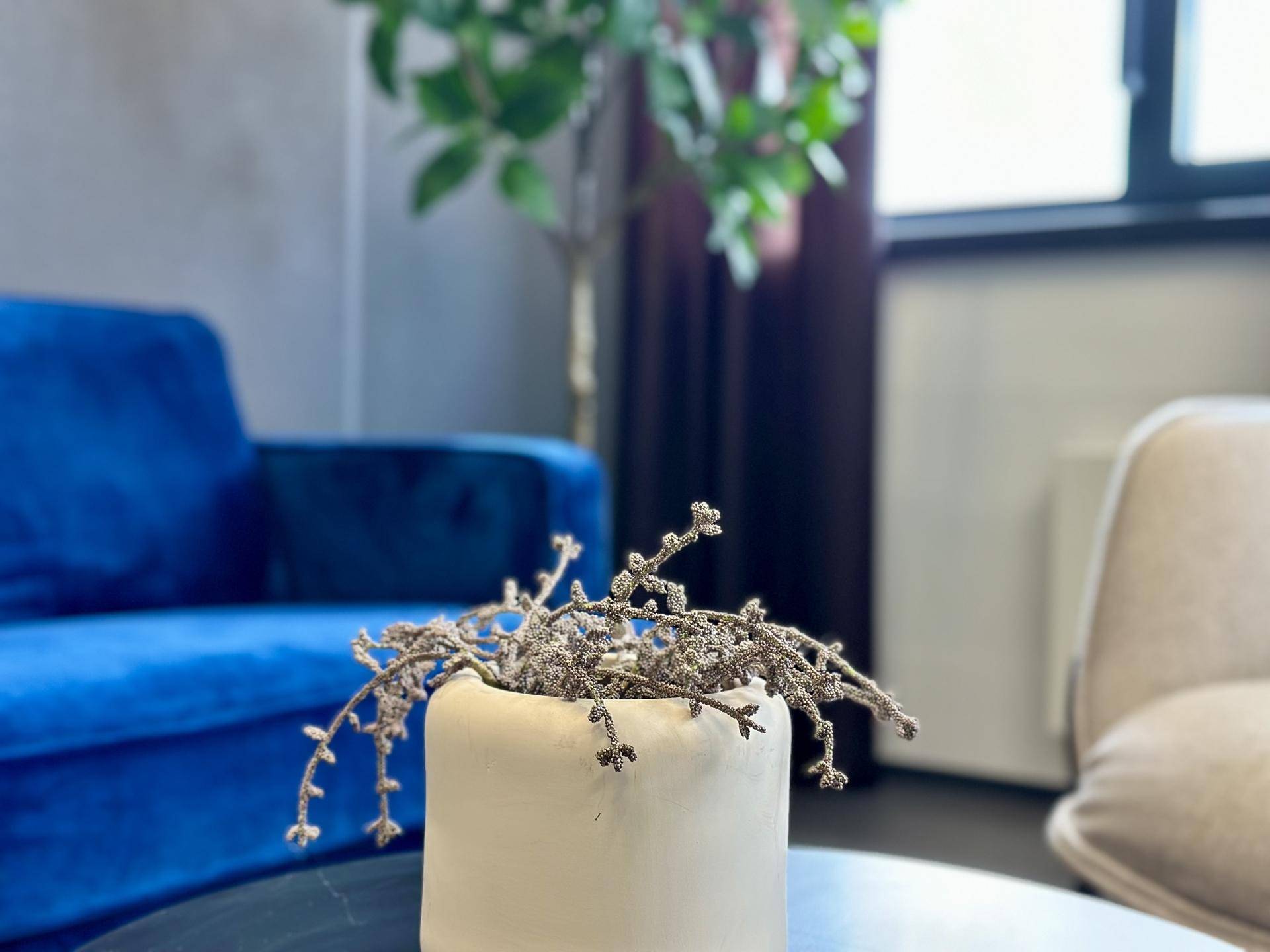 Nahaufnahme einer Dekoration auf einem Beistelltisch mit einem blauen Sofa im Hintergrund.