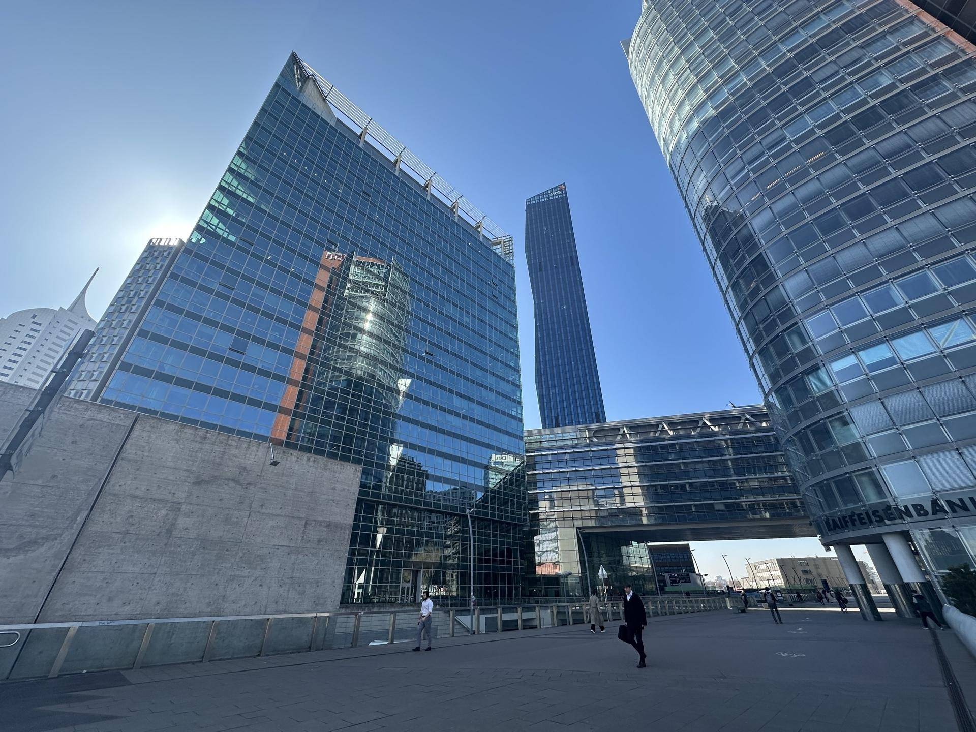 Moderne Bürogebäude mit Glasfassaden und Fußgängerzone an einem sonnigen Tag.