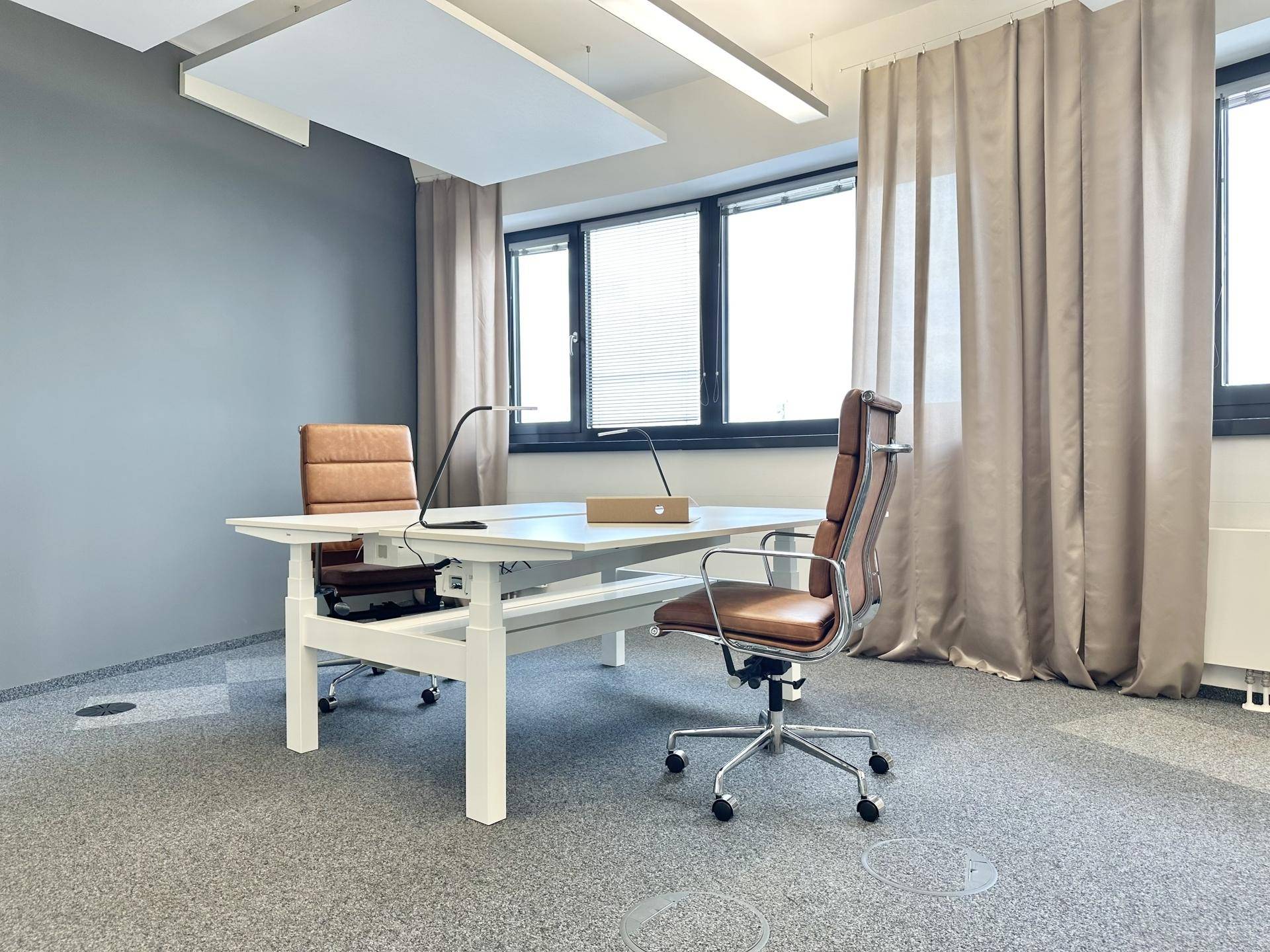 Moderner Arbeitsplatz mit zwei Schreibtischen und Bürostühlen in einem hellen Büroraum.