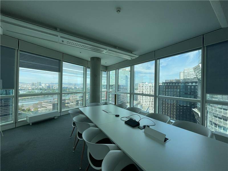Moderner Konferenzraum mit großem Tisch und Panoramablick auf die Stadt und den Fluss.