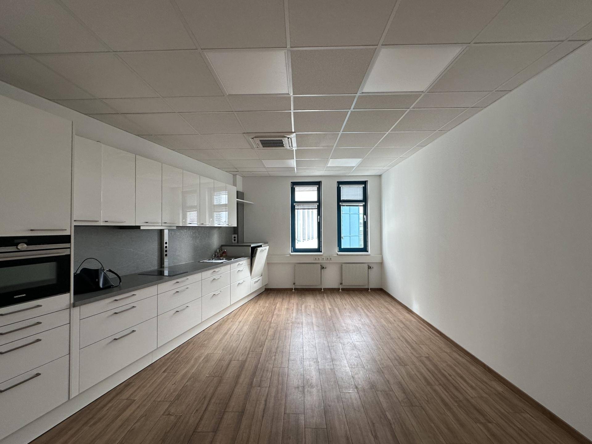 Moderne Einbauküche mit weißen Schränken, integrierten Geräten und Holzboden.