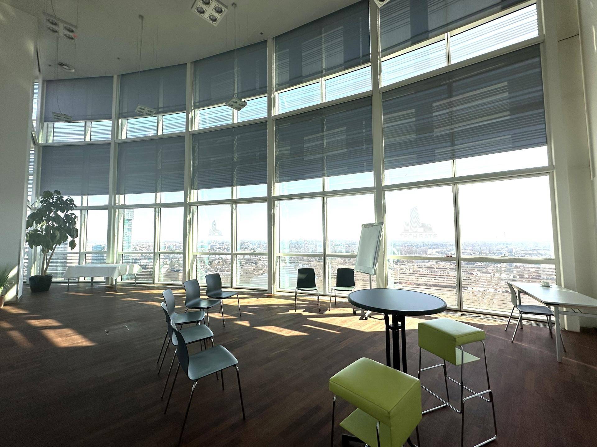 Großer Konferenzraum mit hohen Fenstern, die einen weiten Blick über die Stadt bieten.