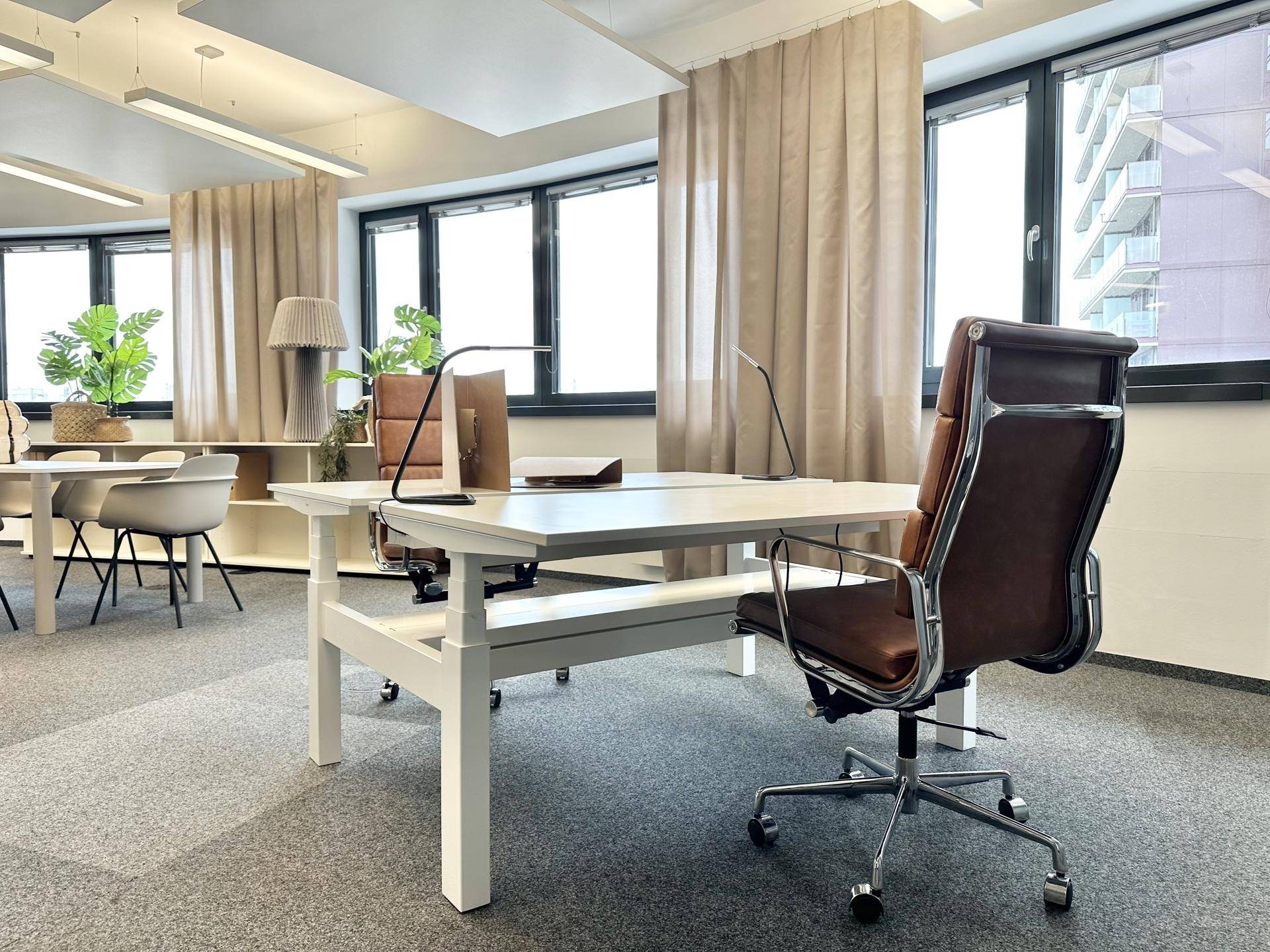 Detailansicht eines modernen Arbeitsplatzes mit höhenverstellbarem Schreibtisch und ergonomischem Bürostuhl.