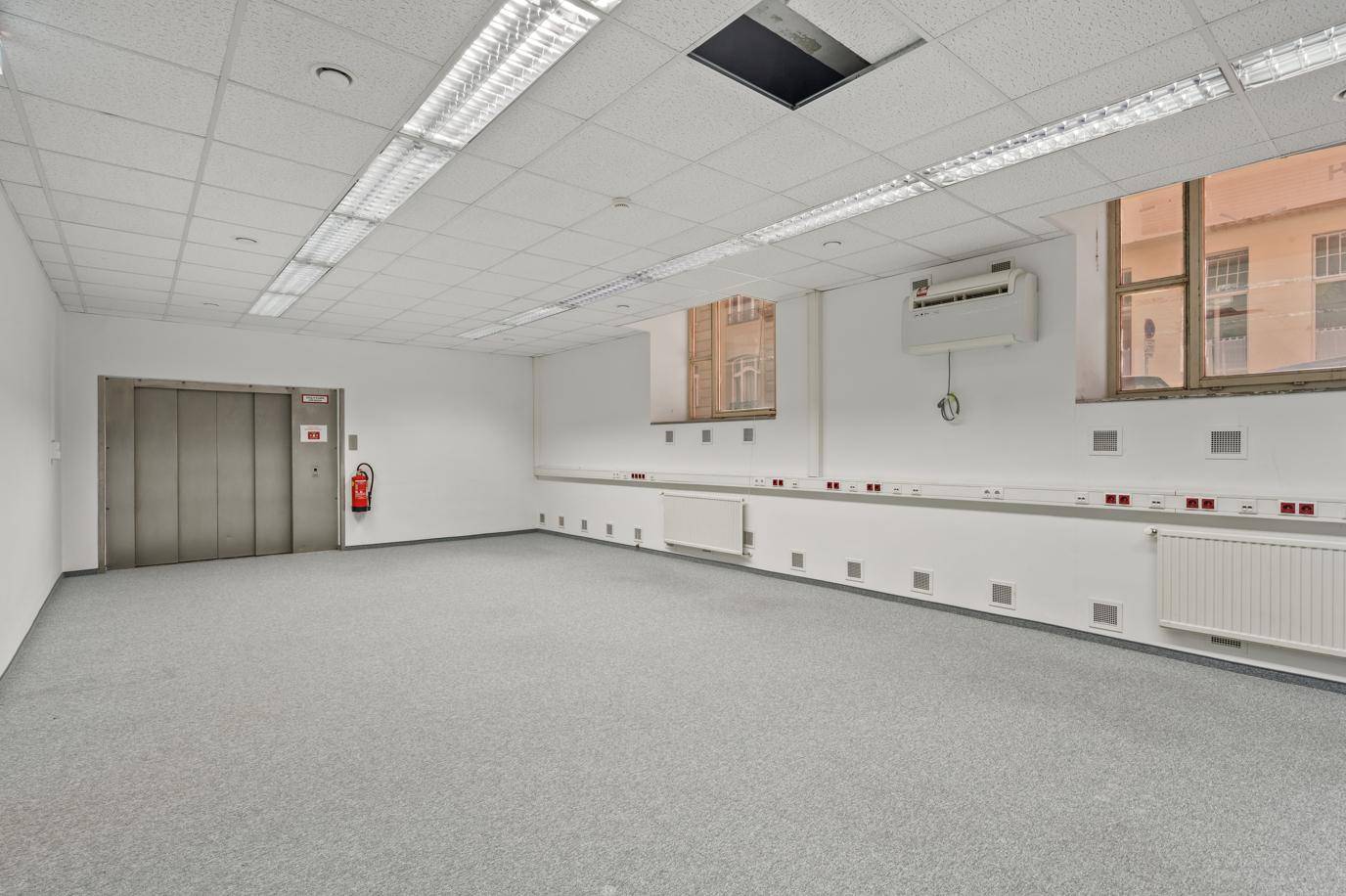 Geräumiger Bürobereich mit Teppichboden, Rasterdecke und integriertem Aufzug.