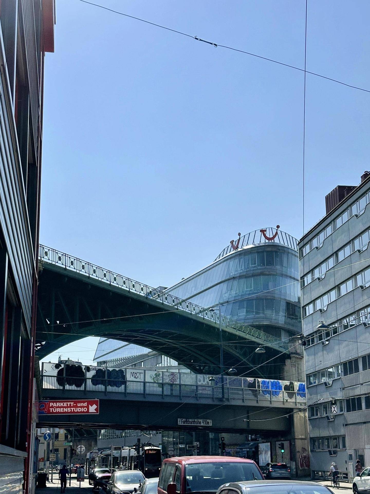 Stadtansicht mit modernen und älteren Gebäuden, Brücken und Straßenverkehr unter blauem Himmel.