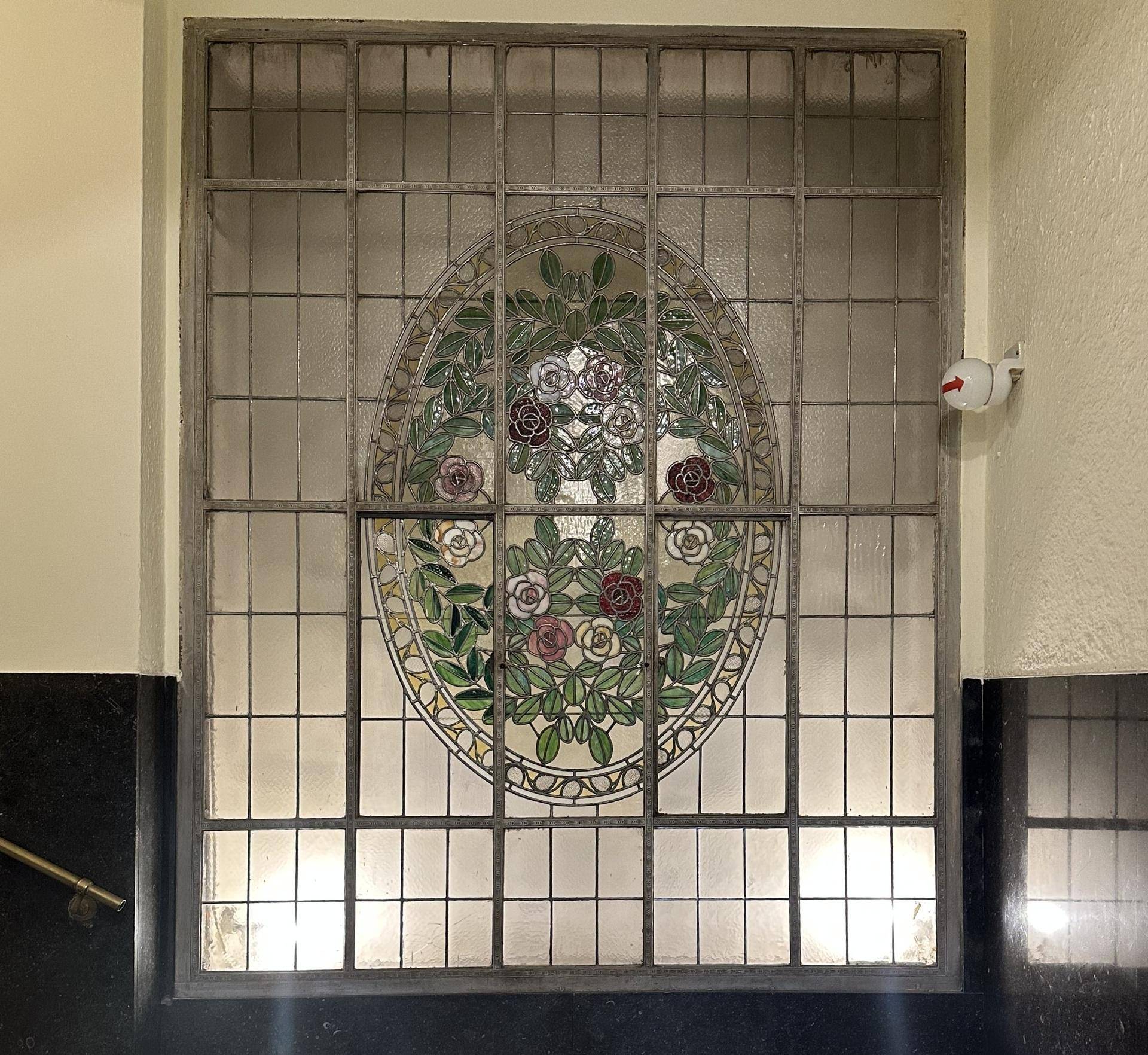 Dekoratives Buntglasfenster mit floralem Muster in einem Flur, das historisches Flair verleiht.