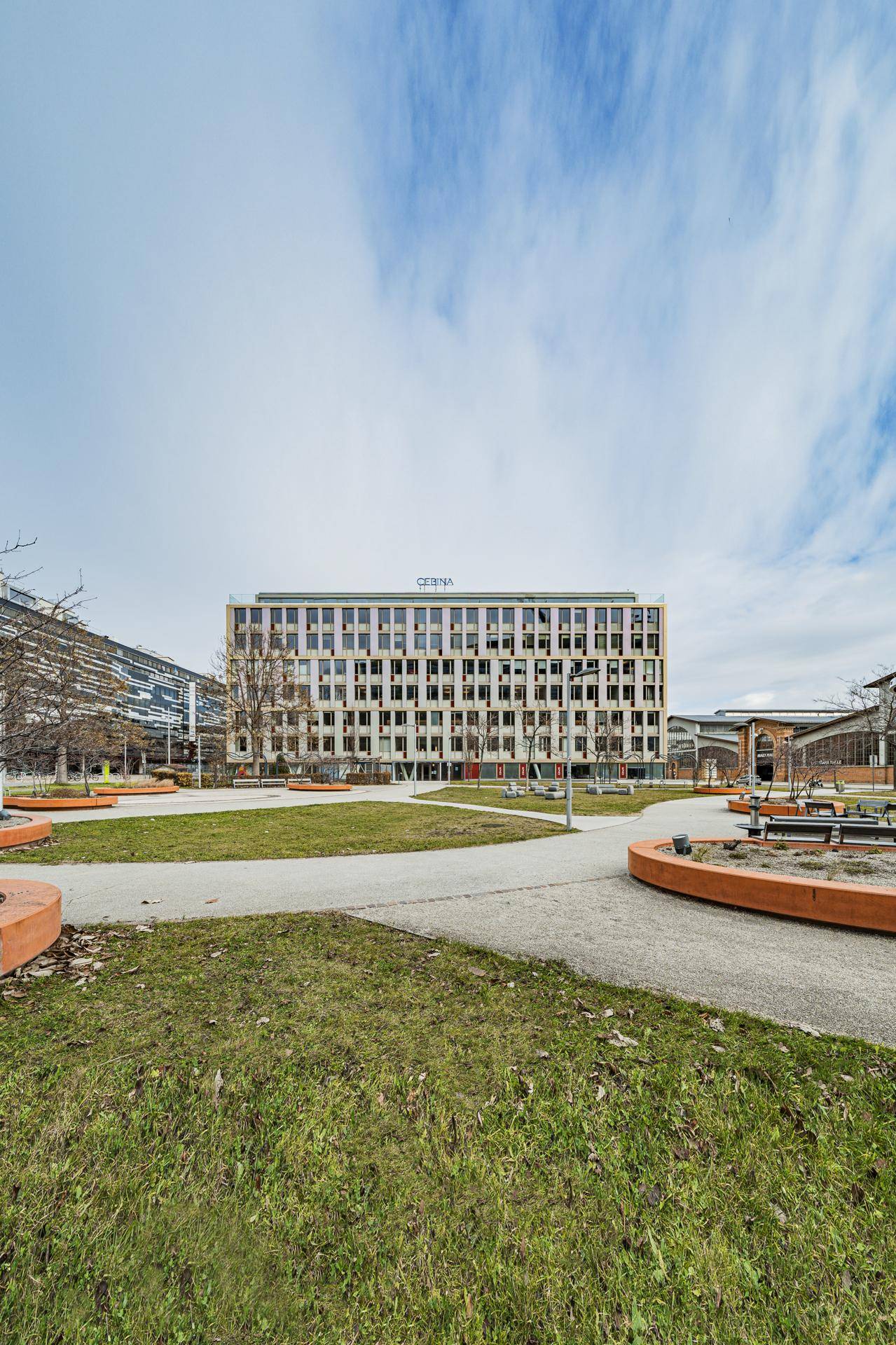 Weitläufige Ansicht des modernen Bürogebäudes mit Parkanlage unter blauem Himmel.