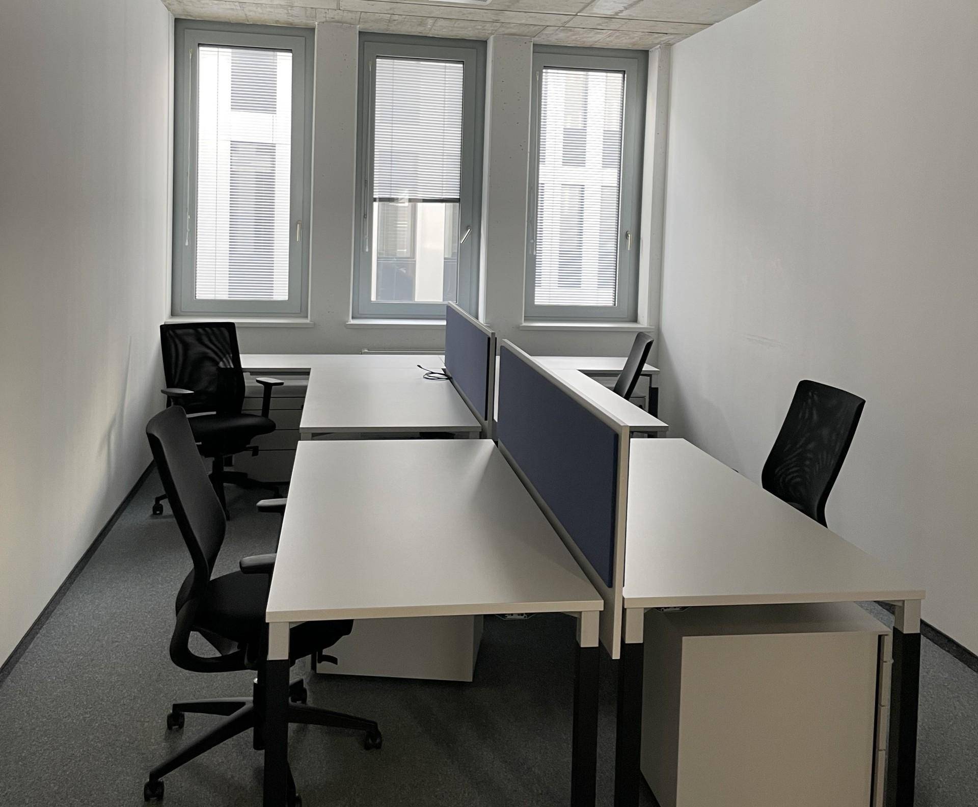 Kompaktes Büro mit zwei Arbeitsplätzen, großen Fenstern und minimalistischer Einrichtung.