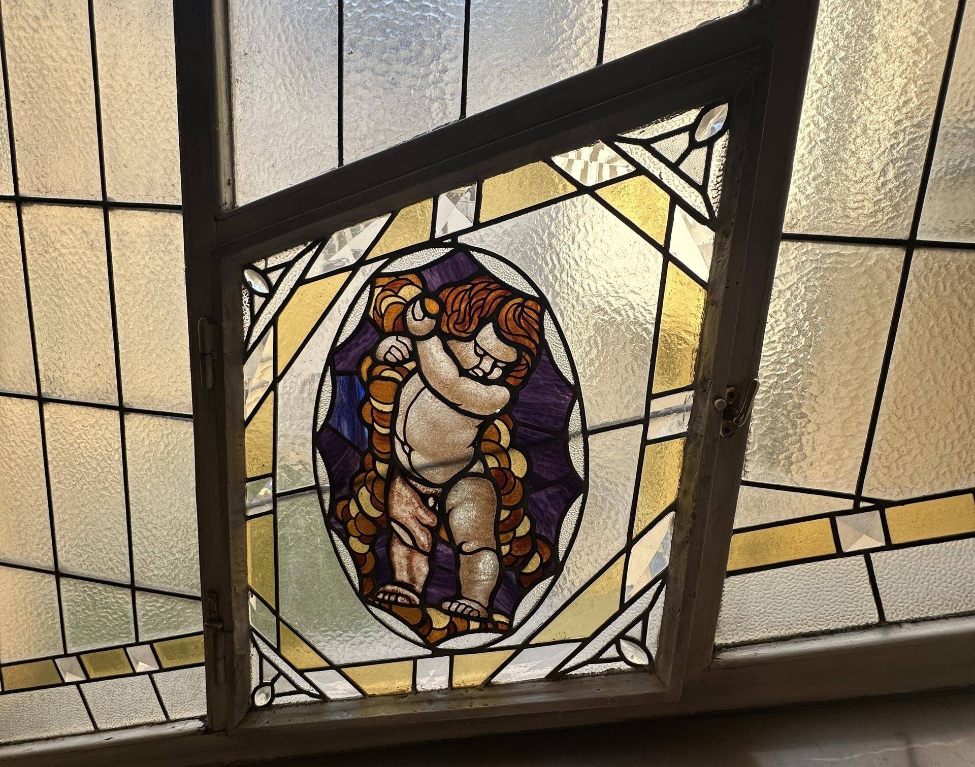 Detail eines Buntglasfensters mit einem klassischen Motiv, das natürliches Licht hereinlässt.