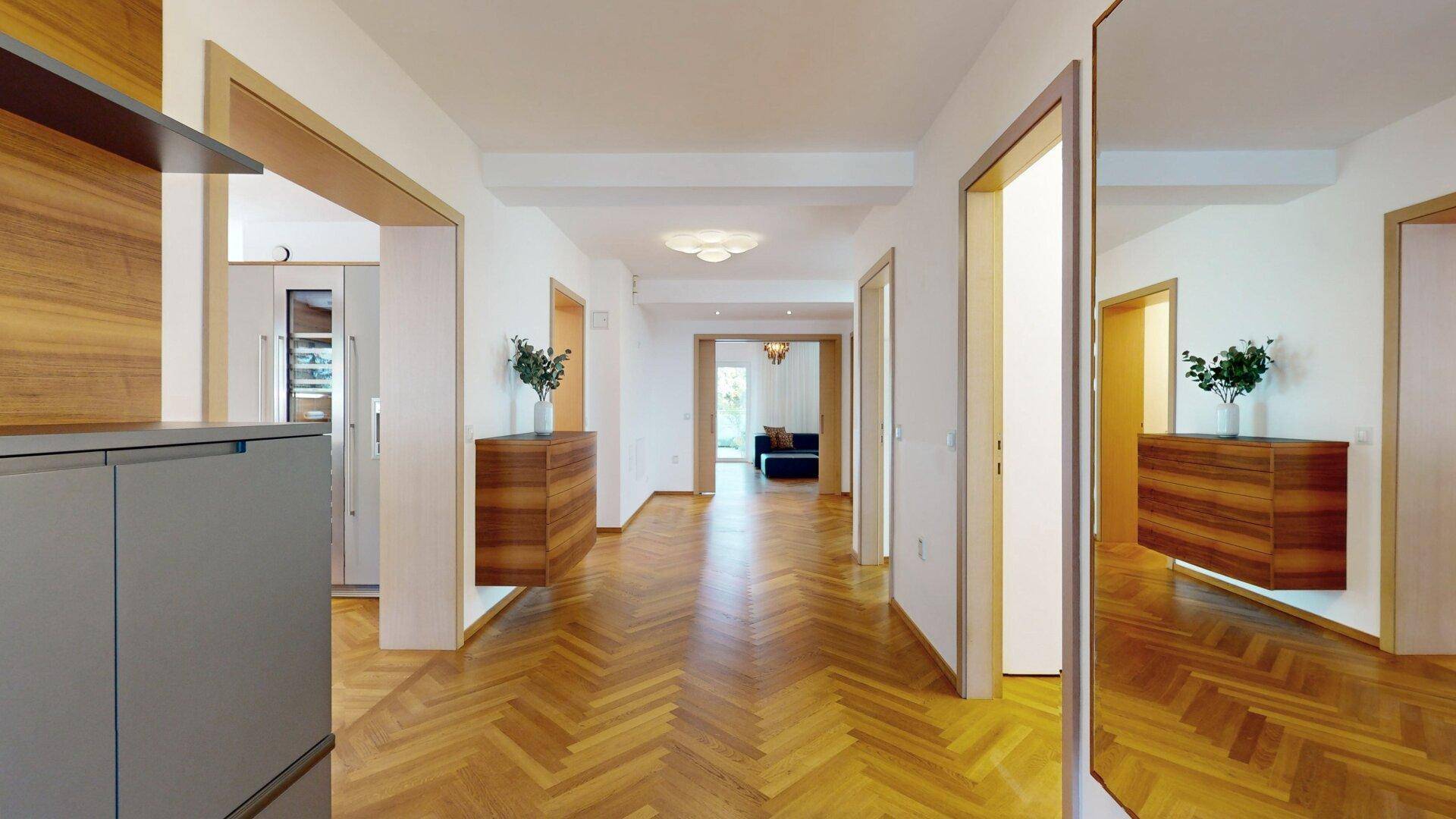 Heller Flur mit Fischgrätparkett und Holzakzenten, der zu verschiedenen Räumen führt.