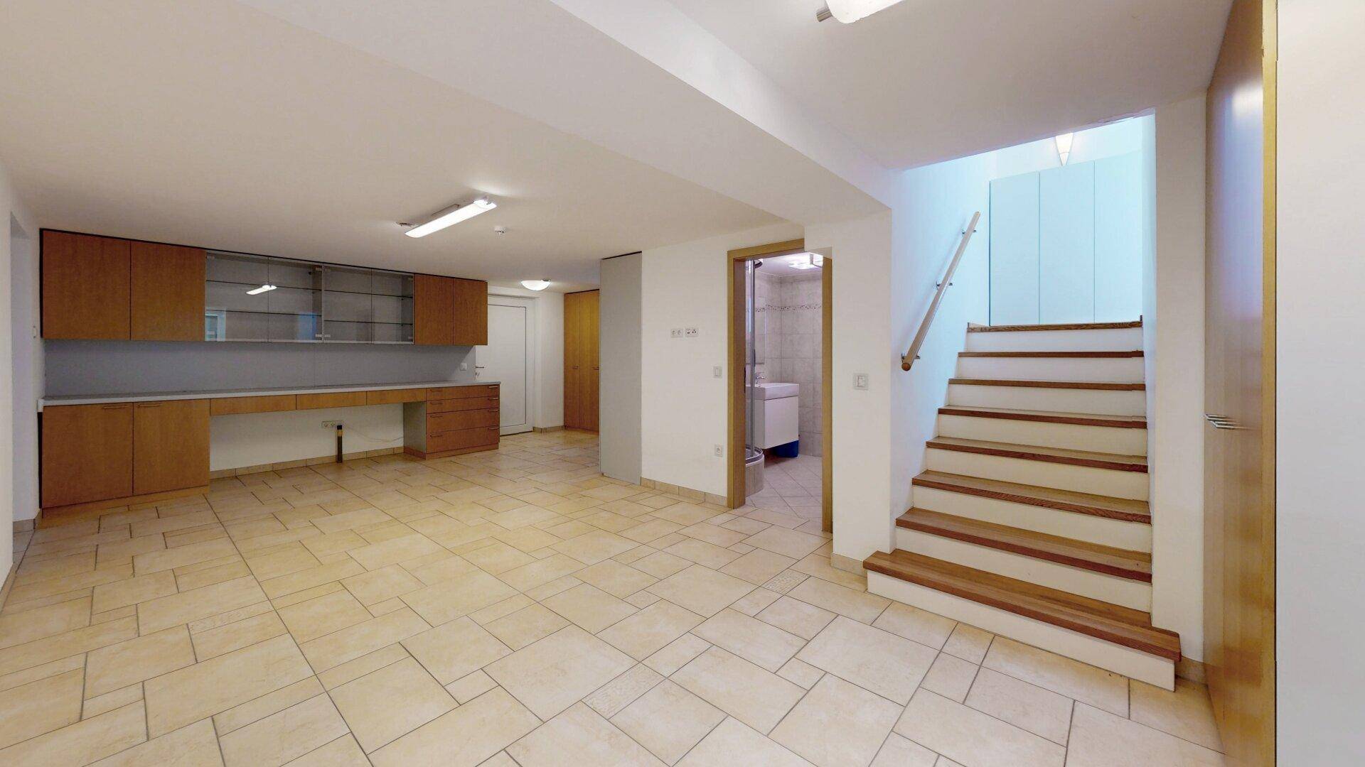 Geräumiger Kellerraum mit Fliesenboden und Einbauschränken, bietet viel Stauraum und Arbeitsfläche.