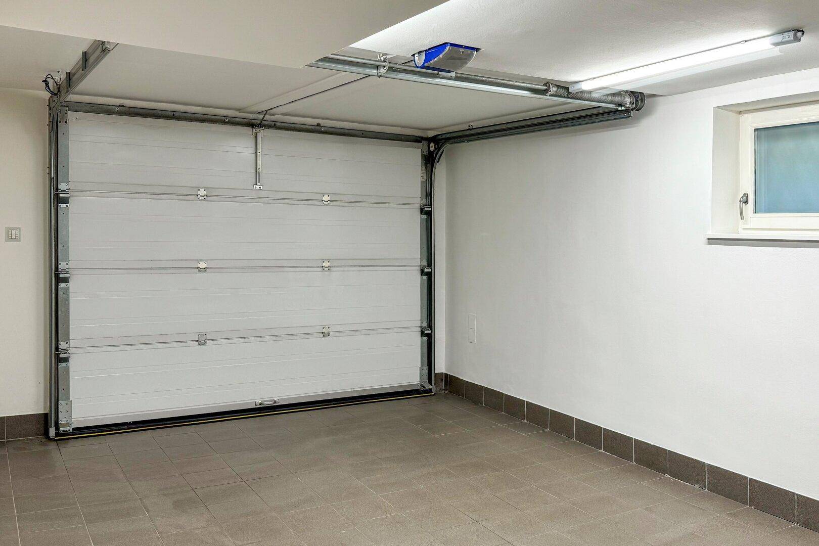 Saubere Garage mit Fliesenboden und automatischem Garagentor, bietet sicheren Stellplatz.