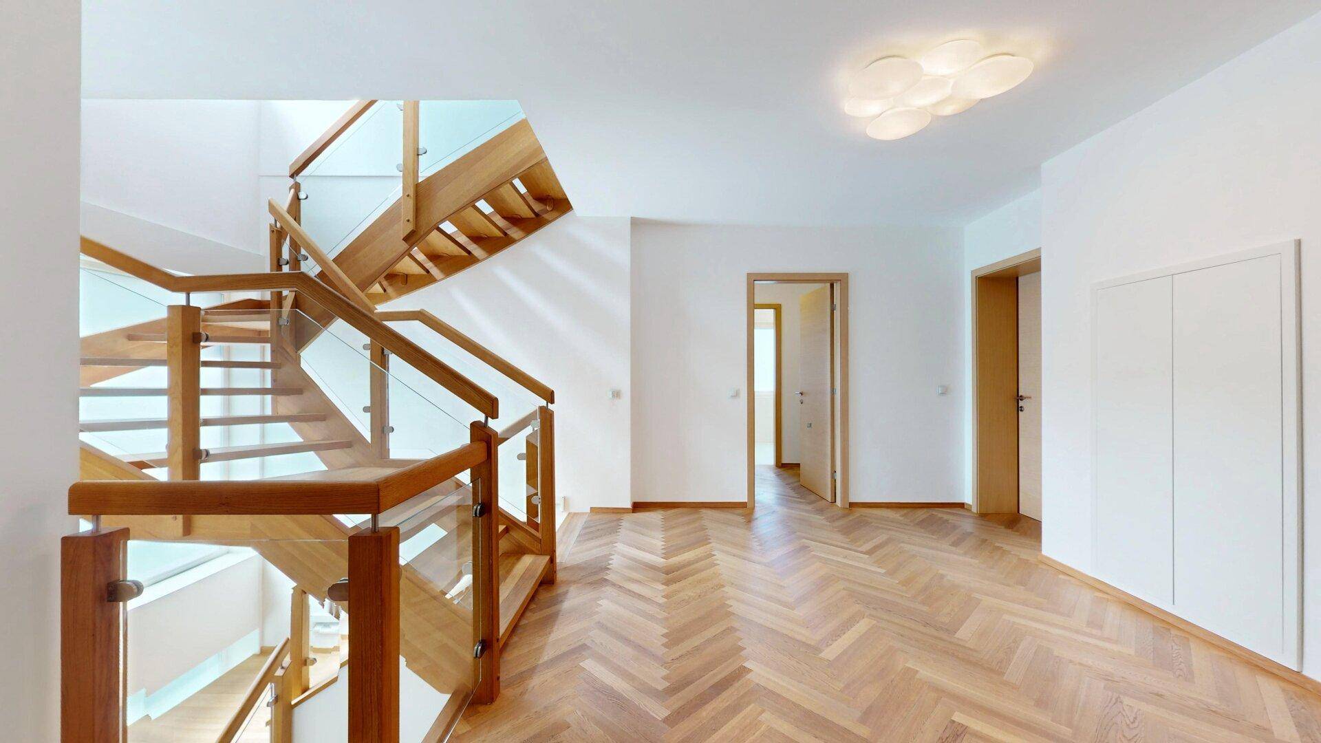 Moderner Treppenaufgang mit Holzstufen und Glasgeländer, der die verschiedenen Ebenen verbindet.