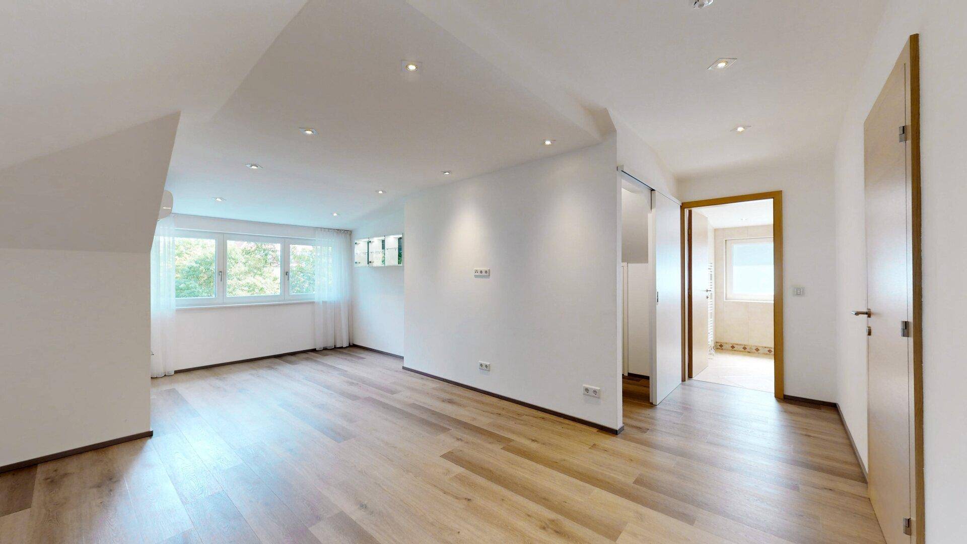 Geräumiger Dachbodenraum mit Holzboden und großen Fenstern, ideal für individuelle Gestaltung.