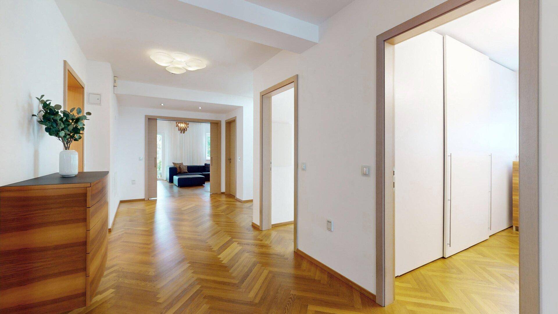 Heller Flur mit Fischgrätparkett und Holzakzenten, der zu verschiedenen Räumen führt.