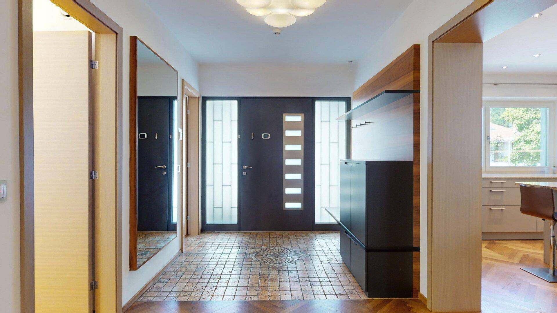 Eingangsbereich mit Fliesenboden und Holzakzenten, führt zu einer modernen Eingangstür.