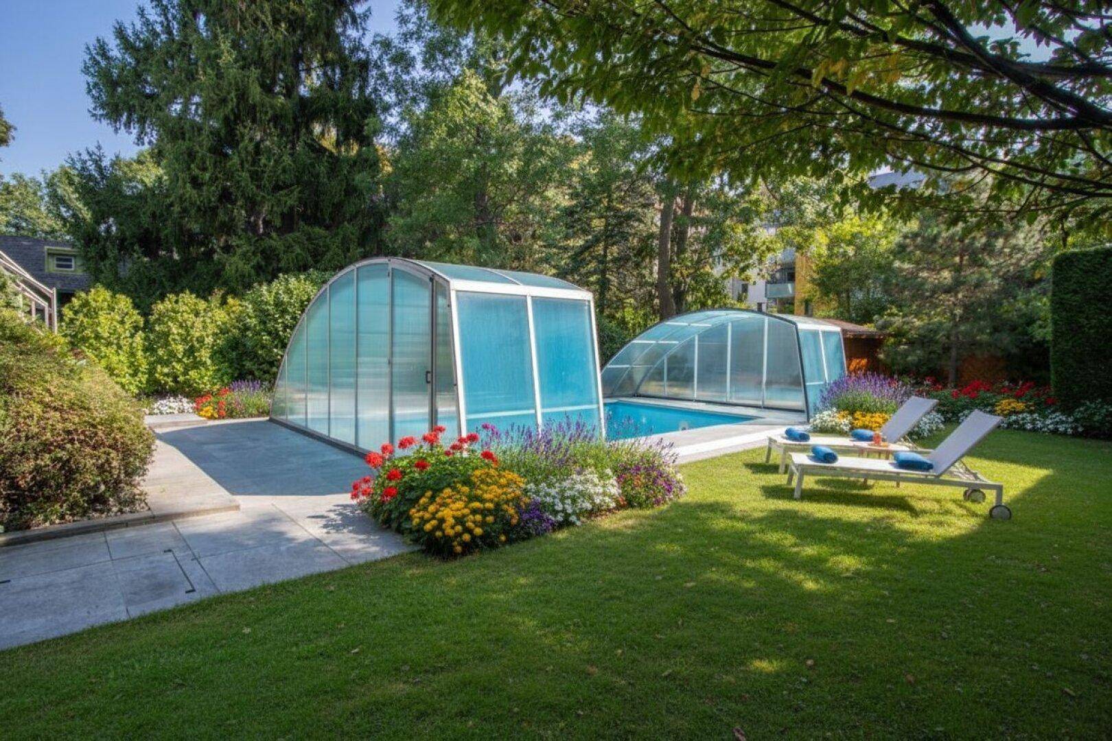 Attraktiver Garten mit zwei überdachten Pools, Liegestühlen und bunten Blumenbeeten.