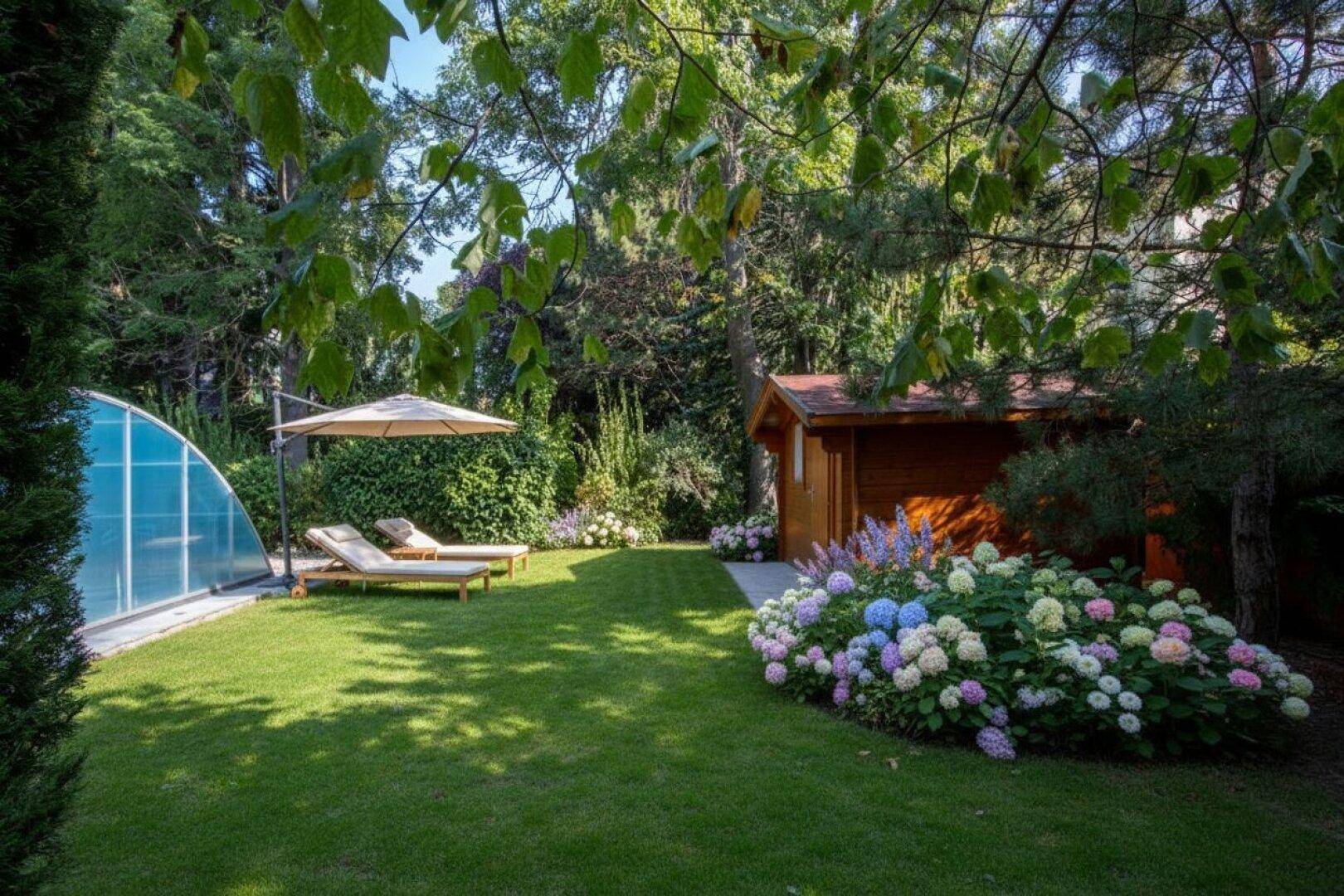 Gepflegter Garten mit Rasen, überdachtem Pool, Gartenhaus und bunten Blumenbeeten unter schattenspendenden Bäumen.