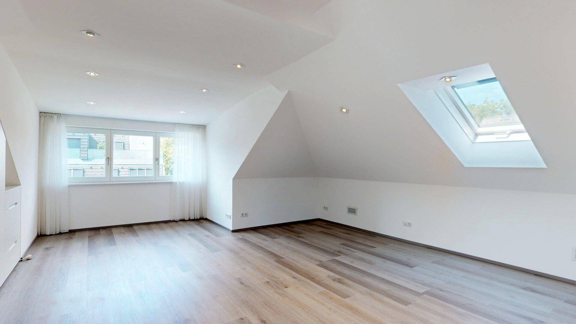 Heller Dachbodenraum mit Holzboden, Dachfenster und großem Fenster, bietet vielseitige Nutzungsmöglichkeiten.