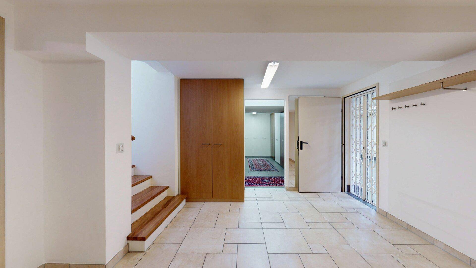 Heller Kellerflur mit Fliesenboden, Einbauschrank und Zugang zu weiteren Räumen.