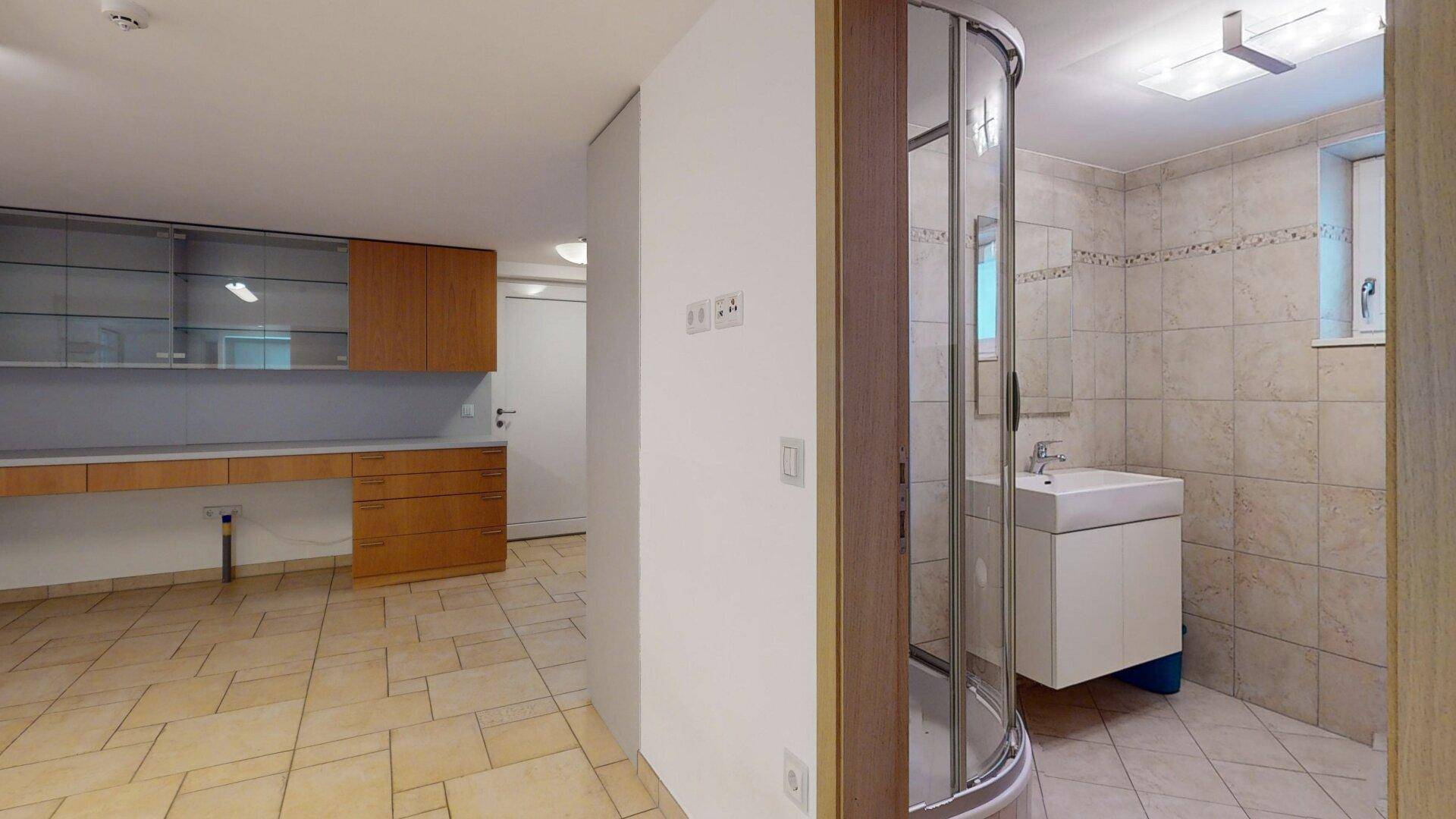 Kellerbad mit Dusche, Waschbecken und Fliesenboden, funktional und hell gestaltet.