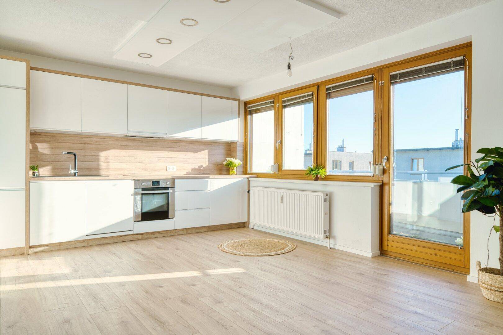 Geräumige, helle Küche mit weißen Schränken, Holzakzenten und viel Tageslicht.