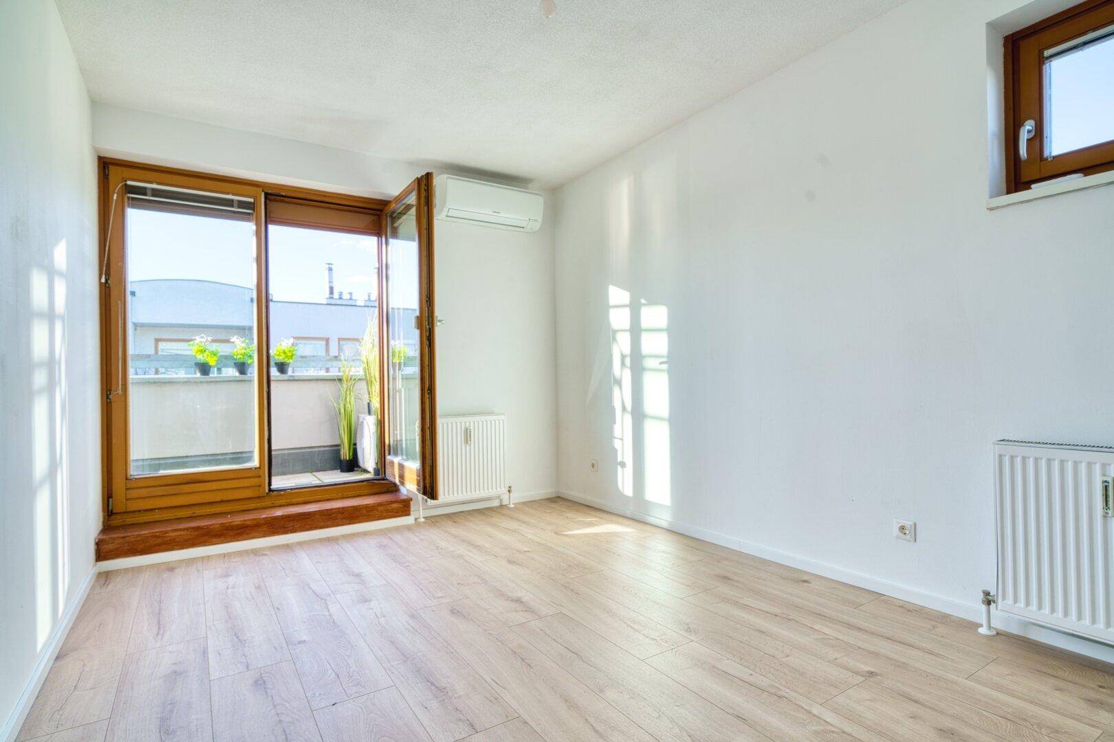 Helles Schlafzimmer mit Balkonzugang, Klimaanlage und viel natürlichem Licht.