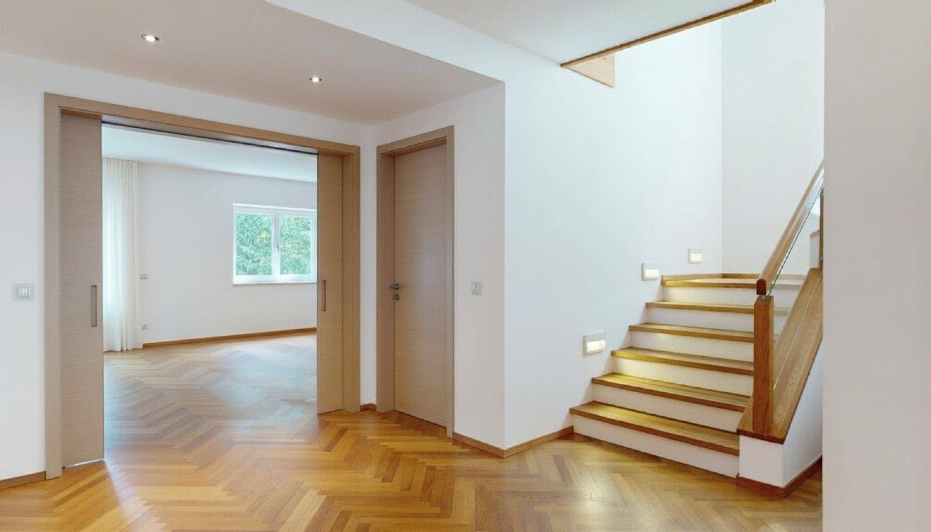 Heller Flur mit Parkettboden, Einbaustrahlern und Zugang zu weiteren Räumen.