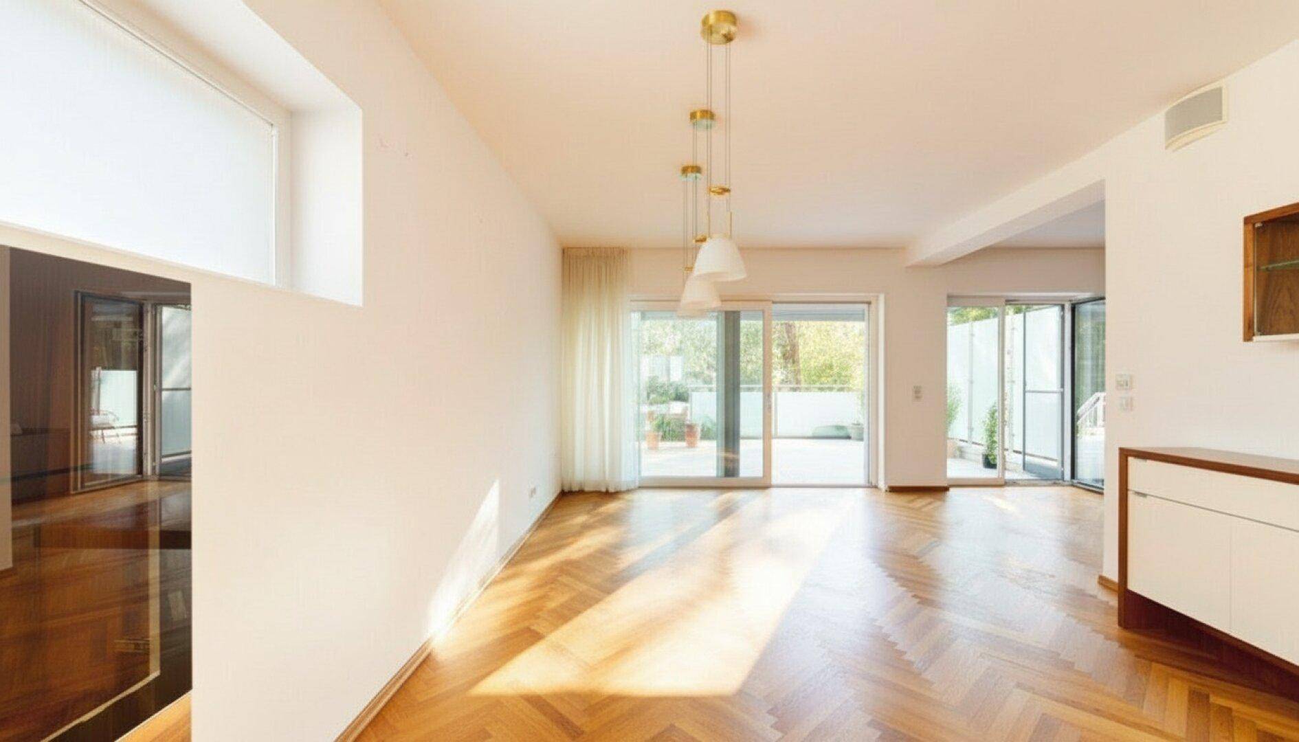 Heller, leerer Raum mit Parkettboden und mehreren Zugängen zu den Außenterrassen.