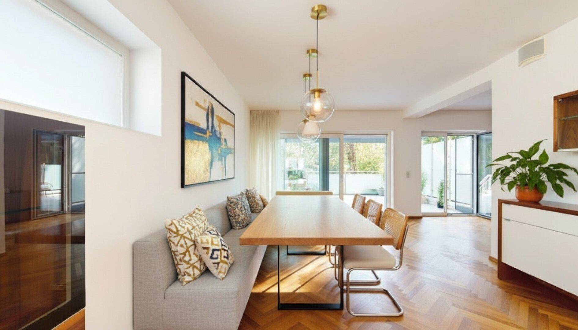 Moderner Essbereich mit langem Holztisch, Sitzbank und Zugang zu einer Außenterrasse.