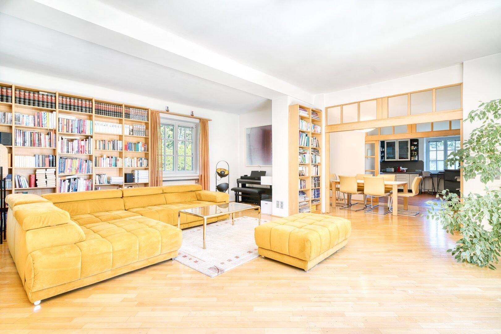 Geräumiger Wohnbereich mit Bücherregalen, Parkettboden und offenem Übergang zum Esszimmer.