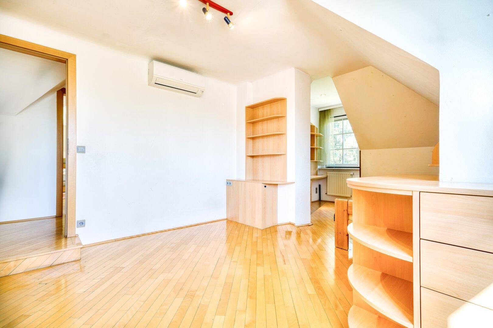 Schlafzimmer mit Parkettboden, Dachschräge und Klimaanlage für angenehmes Raumklima.
