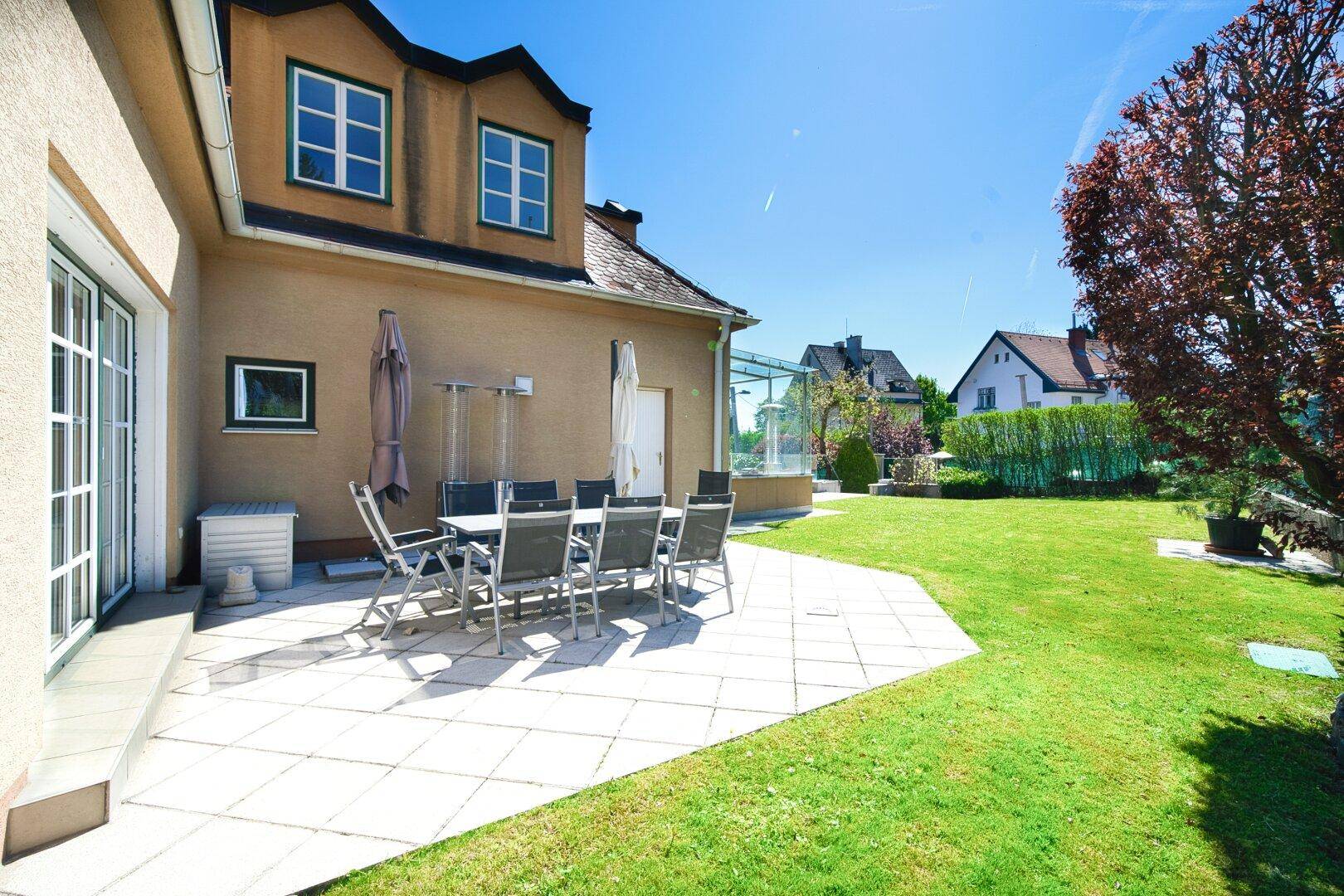 Sonniger Terrassenbereich mit Gartenmöbeln und Blick auf den gepflegten Garten.