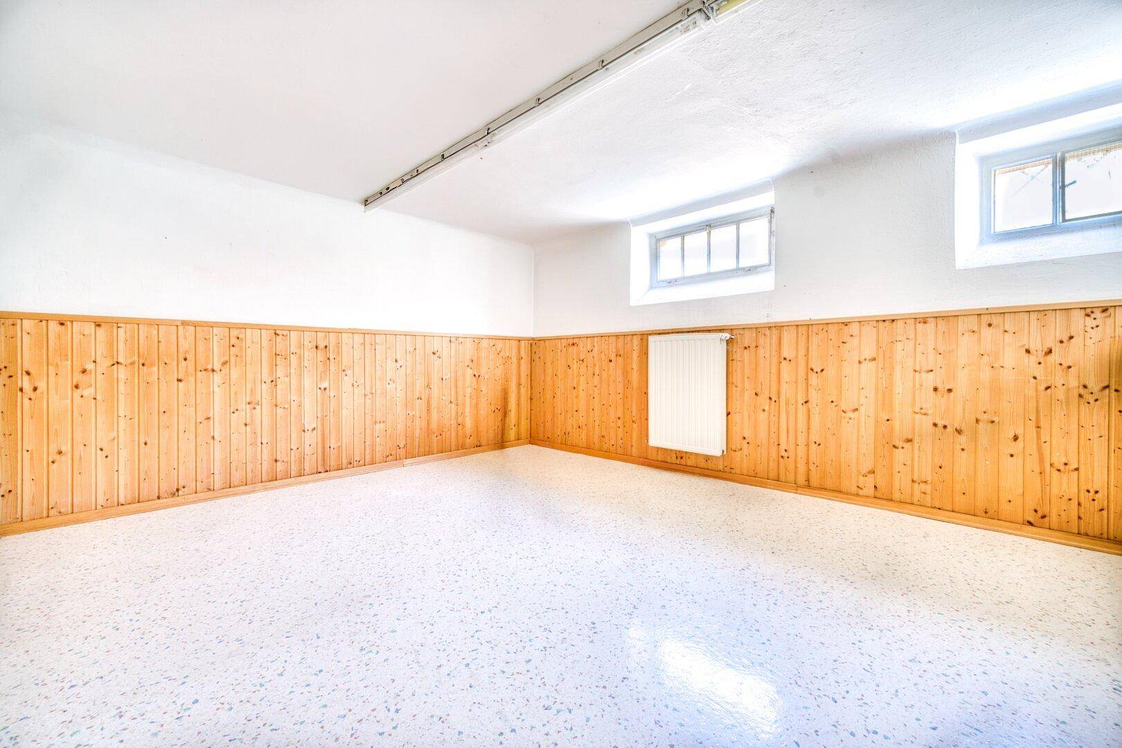 Kellerraum mit Holzvertäfelung und Fenster, vielseitig nutzbar.