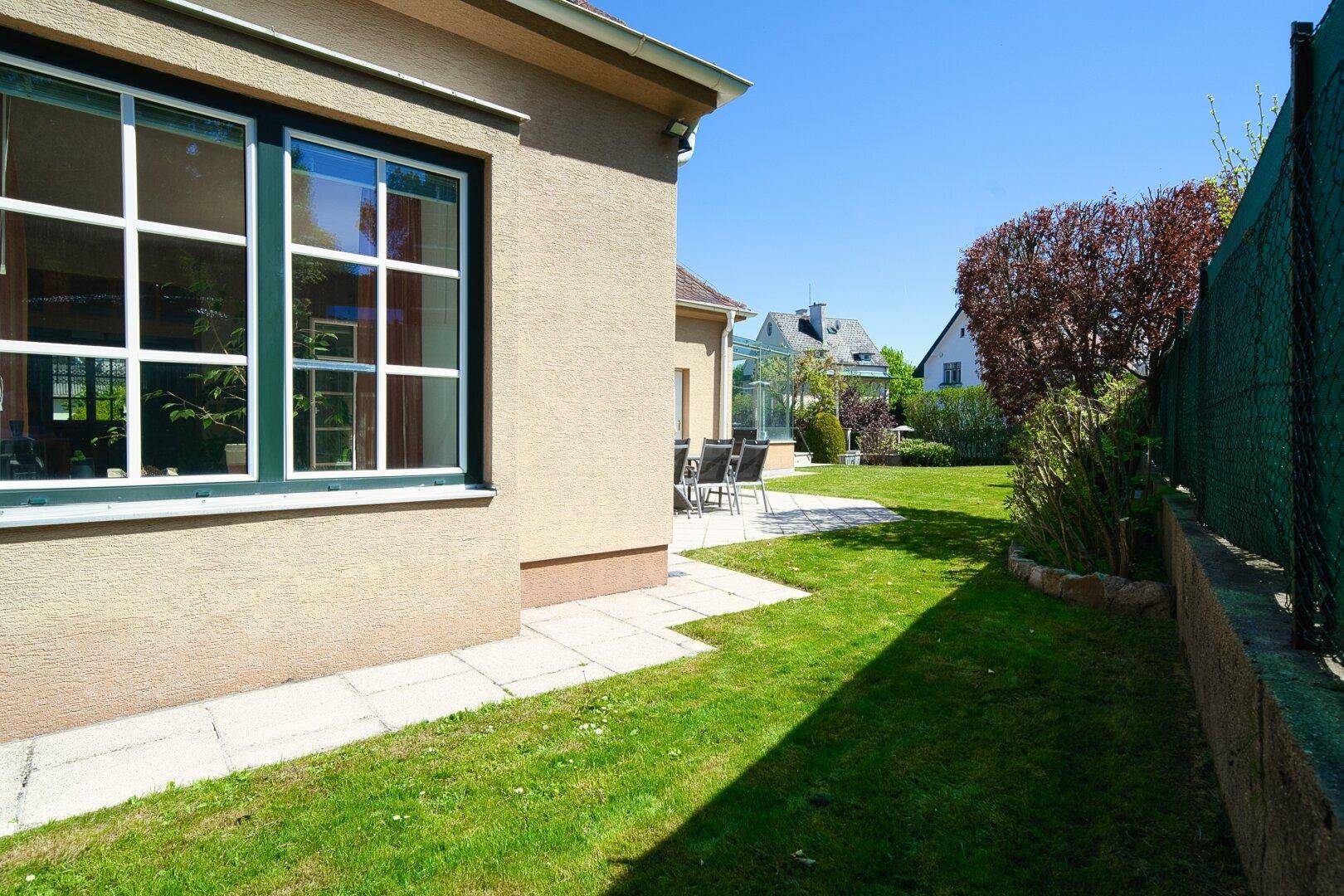 Seitlicher Gartenbereich mit Rasenfläche und Blick auf die Hausfassade.
