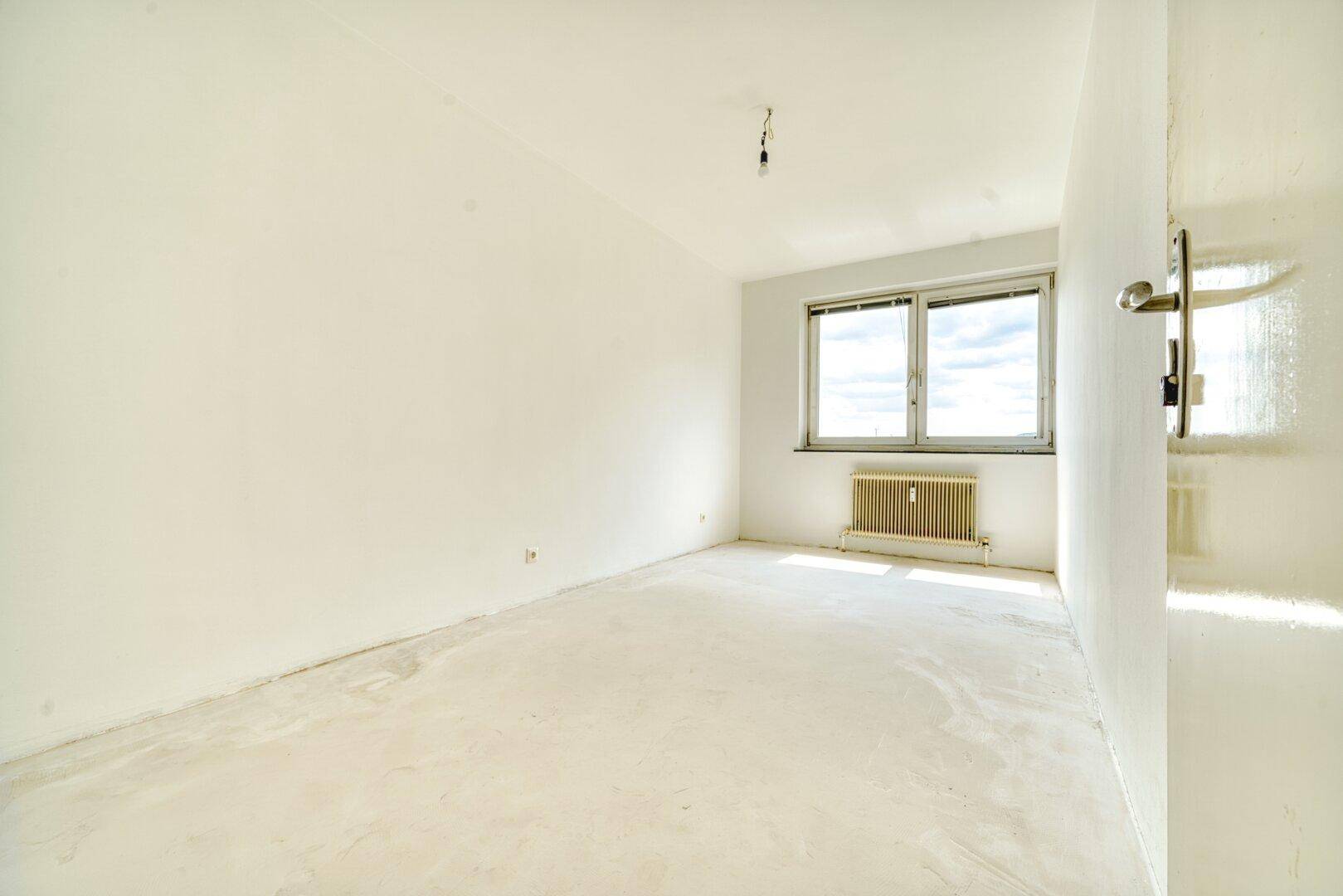 Leeres Schlafzimmer mit weiß gestrichenen Wänden und Fenster.