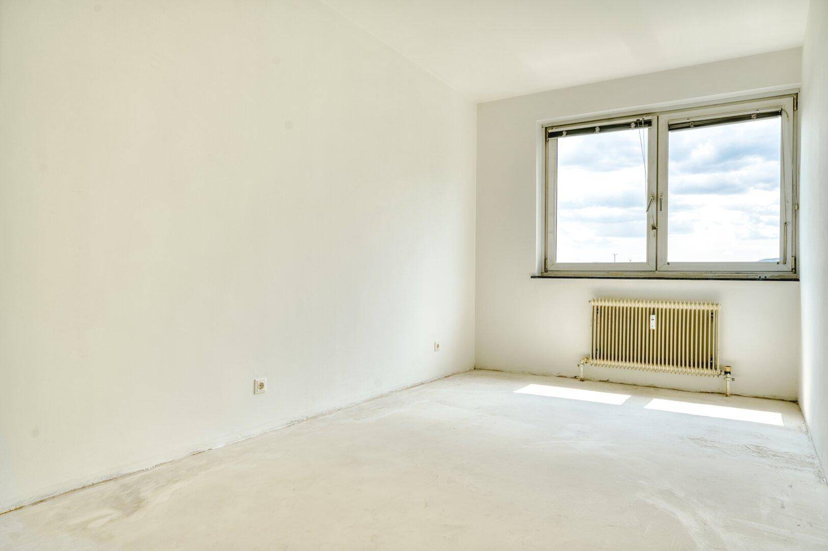 Helles Schlafzimmer mit weiß gestrichenen Wänden und großem Fenster.
