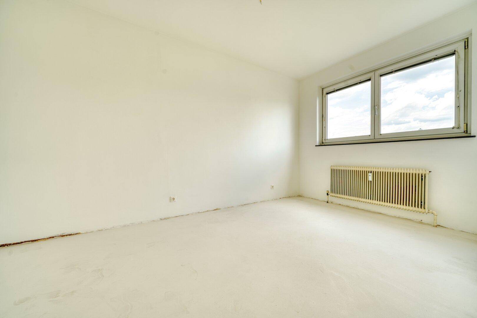 Leeres Schlafzimmer mit weiß gestrichenen Wänden und Fenster.