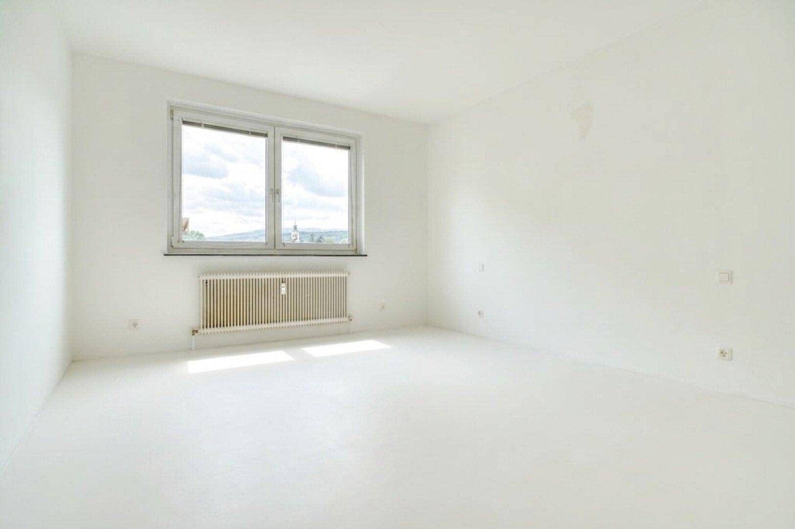 Helles Schlafzimmer mit weiß gestrichenen Wänden und großem Fenster.