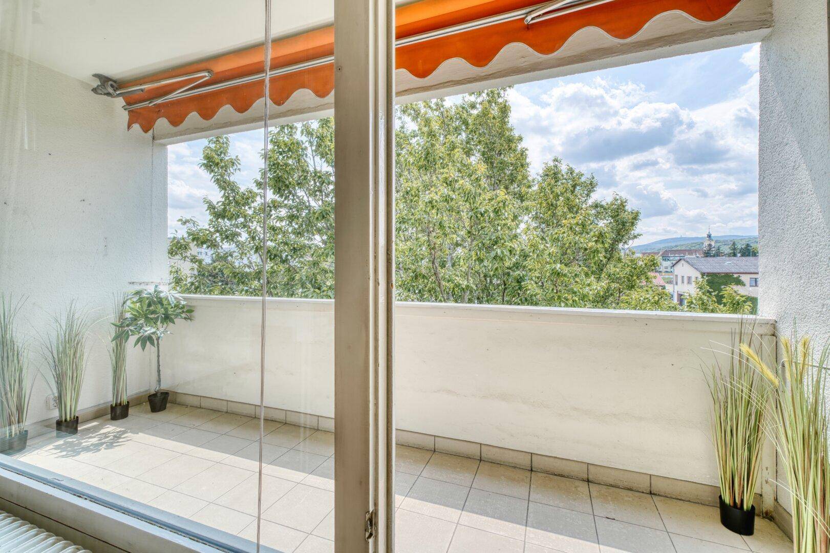 Geräumiger Balkon mit Fliesenboden und Markise, bereit für individuelle Gestaltung.