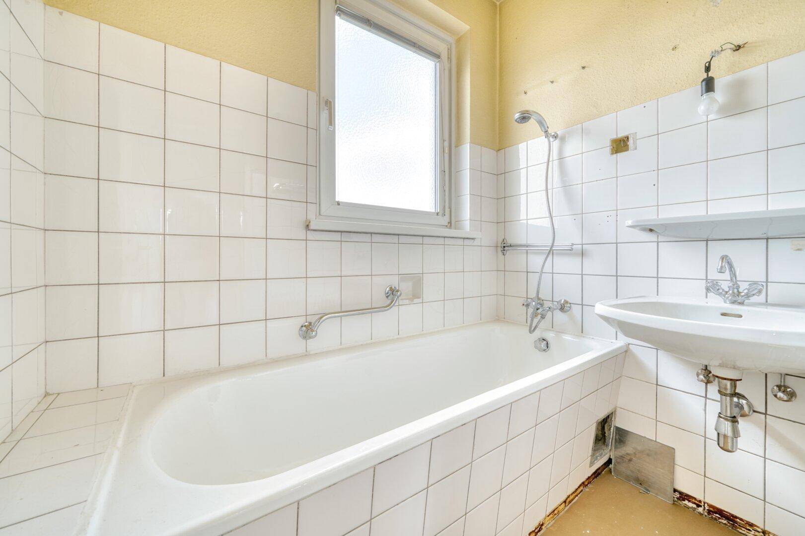Badezimmer mit Badewanne, Waschbecken und weißen Fliesen an den Wänden.