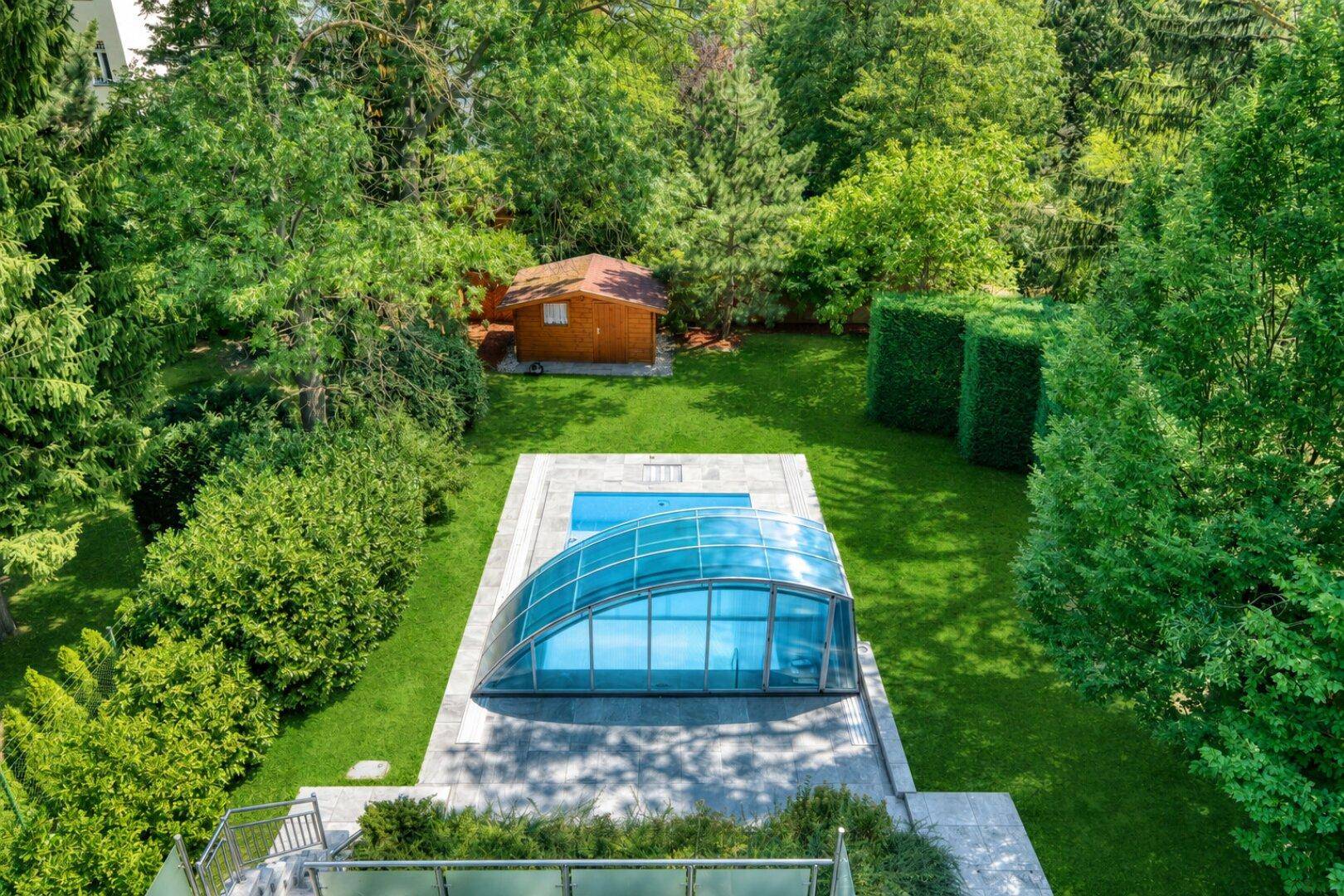 Vogelperspektive des Gartens mit Swimmingpool, Schiebeüberdachung und Gartenhaus.