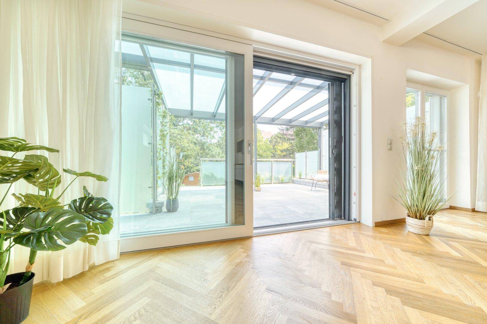 Wohnbereich mit großen Schiebetüren, die zu einer überdachten Terrasse führen.