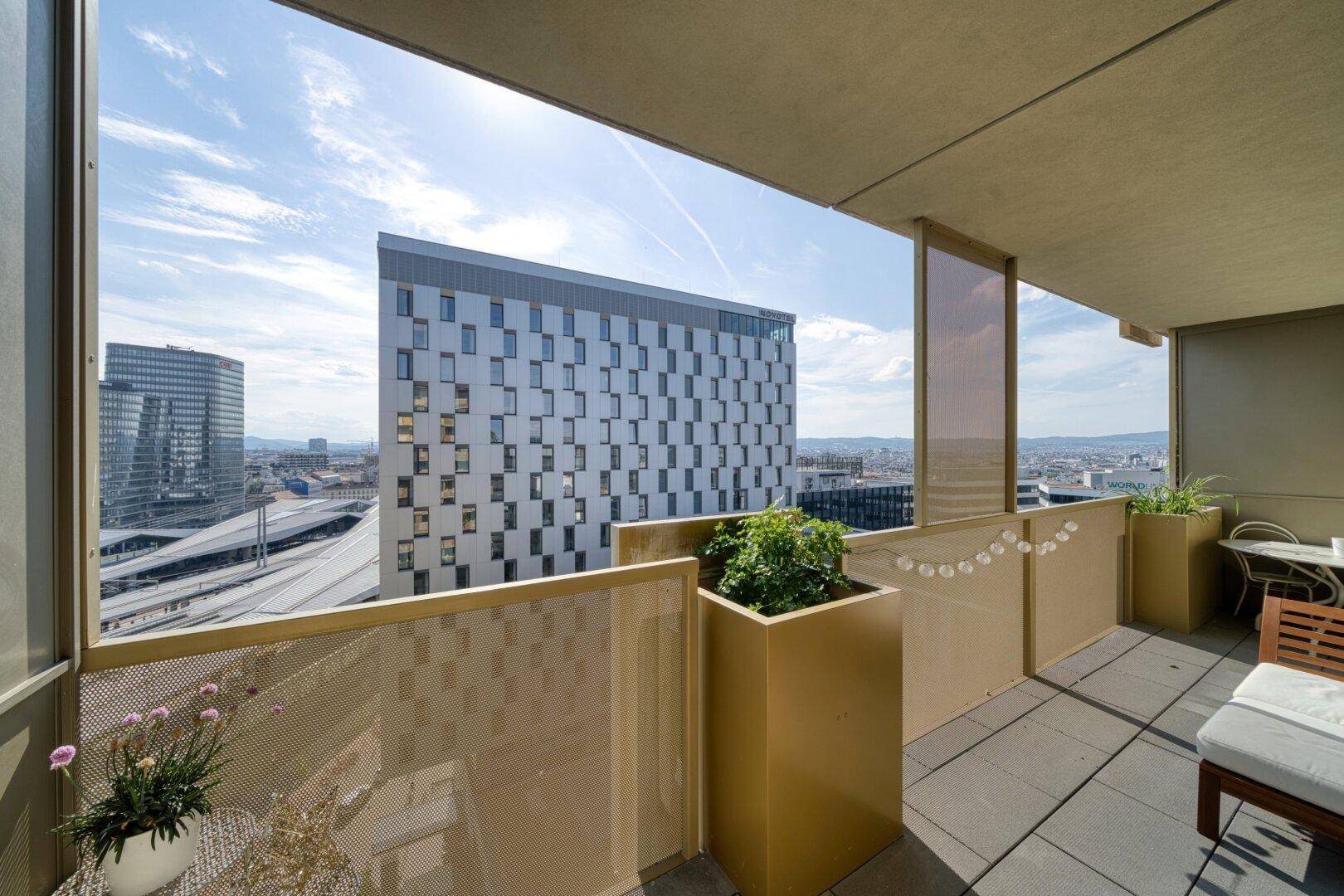 Geräumiger Balkon mit Blick auf die moderne Stadtarchitektur und den weiten Himmel.